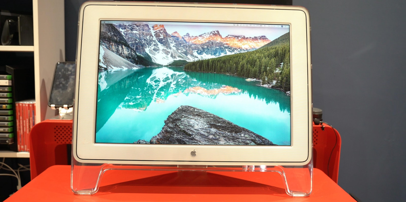透明外壳的 Apple Cinema Display 放在红色桌面上